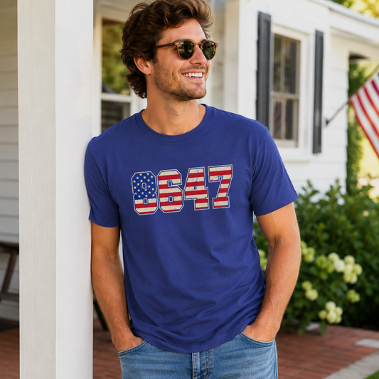 Man wearing a blue t-shirt with '8647' design, standing outdoors.