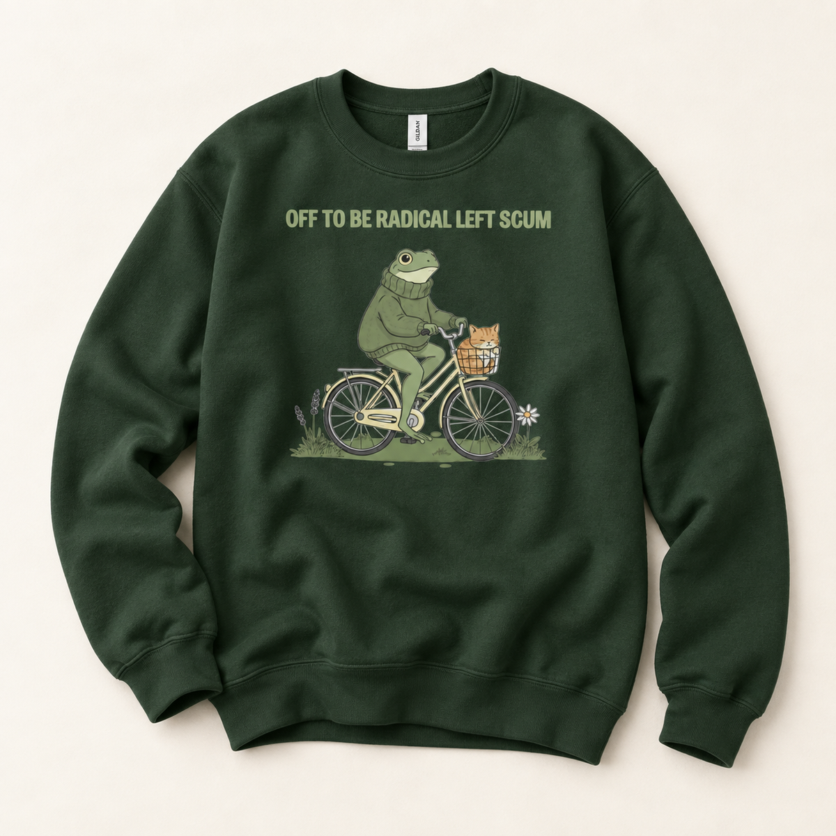 A dark green crewneck sweatshirt featuring a graphic of a frog riding a bicycle with a cat in the basket, with the text 'OFF TO BE RADICAL LEFT SCUM' printed above the illustration.