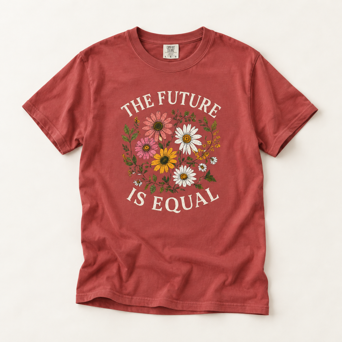 A rust red short-sleeve t-shirt with a graphic print that reads 'THE FUTURE IS EQUAL' in white arched text surrounding a colorful floral design. The shirt is laid flat on a light beige background.