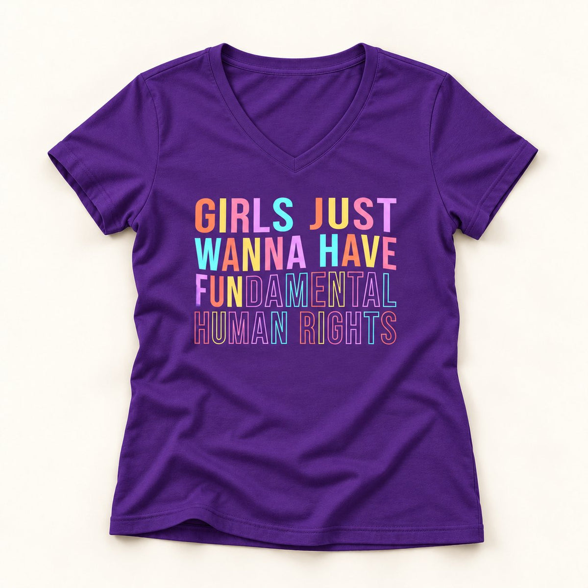 Girls Just Wanna Have Fundamental Human Rights V-Neck T-Shirt in Purple, flat lay on warm off-white background