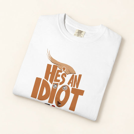 He's An Idiot T-Shirt, product photo on warm off-white background