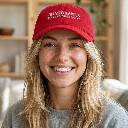 Person wearing a red cap with 'IMMIGRANTS MAKE AMERICA GREAT' text in a casual indoor setting.