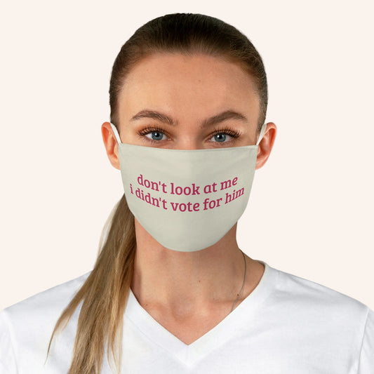 A woman wearing a light beige fabric face mask with pink text that reads 'don't look at me I didn't vote for him'.