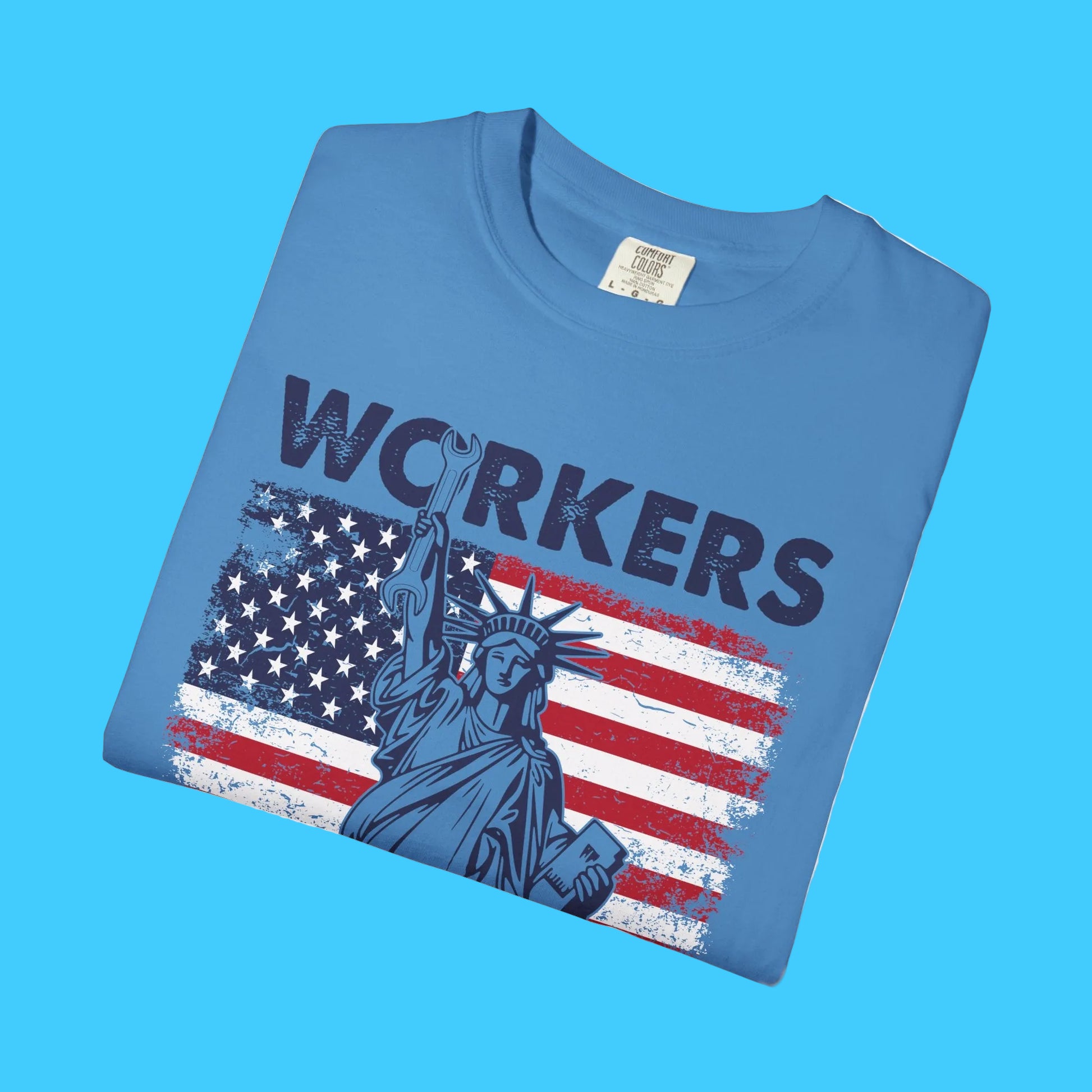 Folded blue t-shirt with 'WORKERS' and Statue of Liberty graphic on a white background