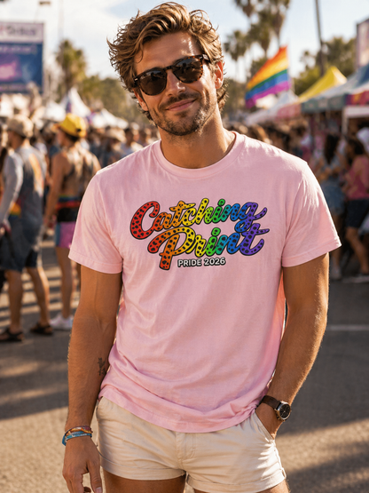 Man wearing a pink t-shirt with colorful text at a Pride event.