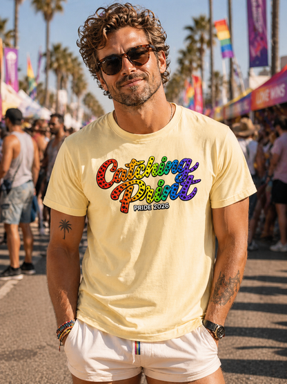 Man wearing a yellow t-shirt with colorful text at a Pride event.