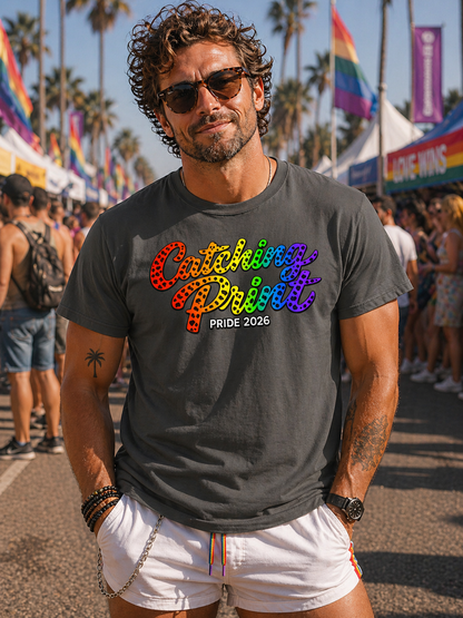 Man wearing a colorful 'Pride 2026' t-shirt at a festival with palm trees and rainbow flags in the background.