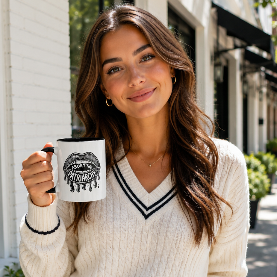Preppy girl holding mug that reads "abort the patriarchy".

