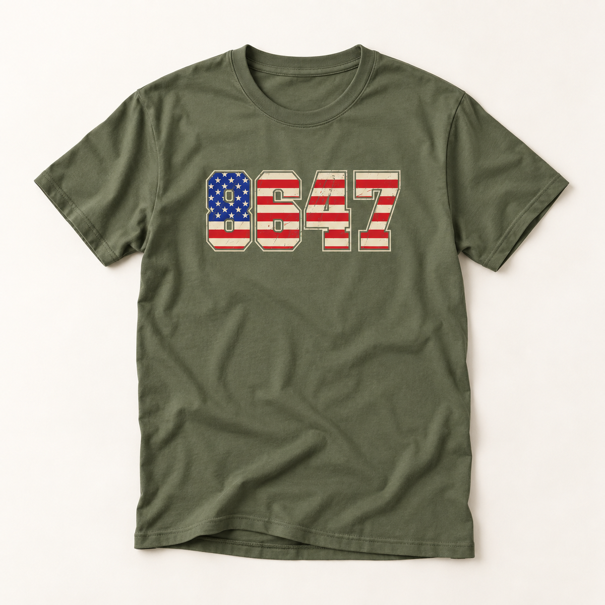 An olive green short-sleeve t-shirt with a graphic on the chest featuring the number 8647 filled with an American flag pattern (red and white stripes and a blue field with white stars).