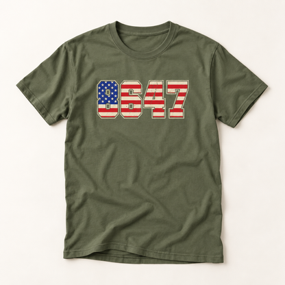 An olive green short-sleeve t-shirt with a graphic on the chest featuring the number 8647 filled with an American flag pattern (red and white stripes and a blue field with white stars).